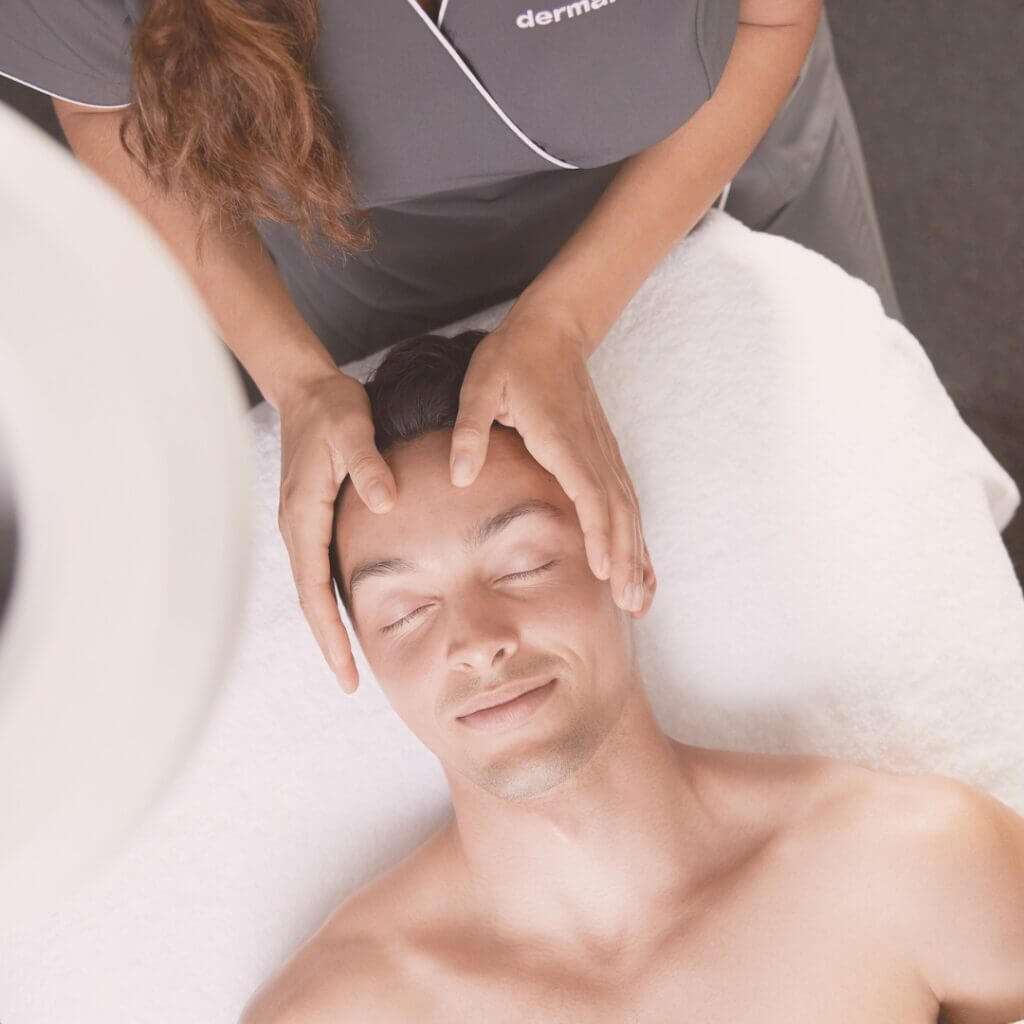 En man som ligger på ett massagebord och får massage i ansiktet